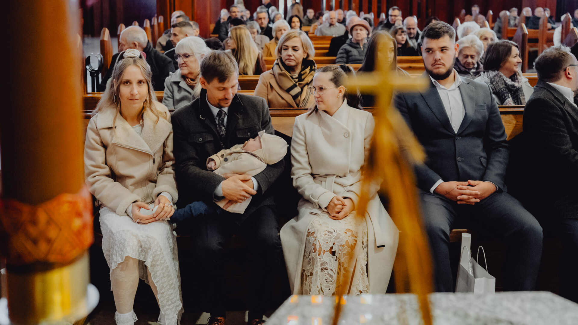 Rodzina siedzi na ławce i czeka na chrzest w kościele NMP matki kościoła w Białymstoku.