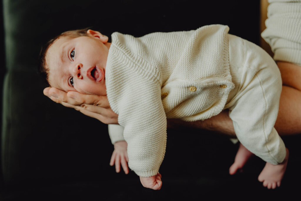 2 tygodniowe dziecko leży na dłoni swojego ojca.