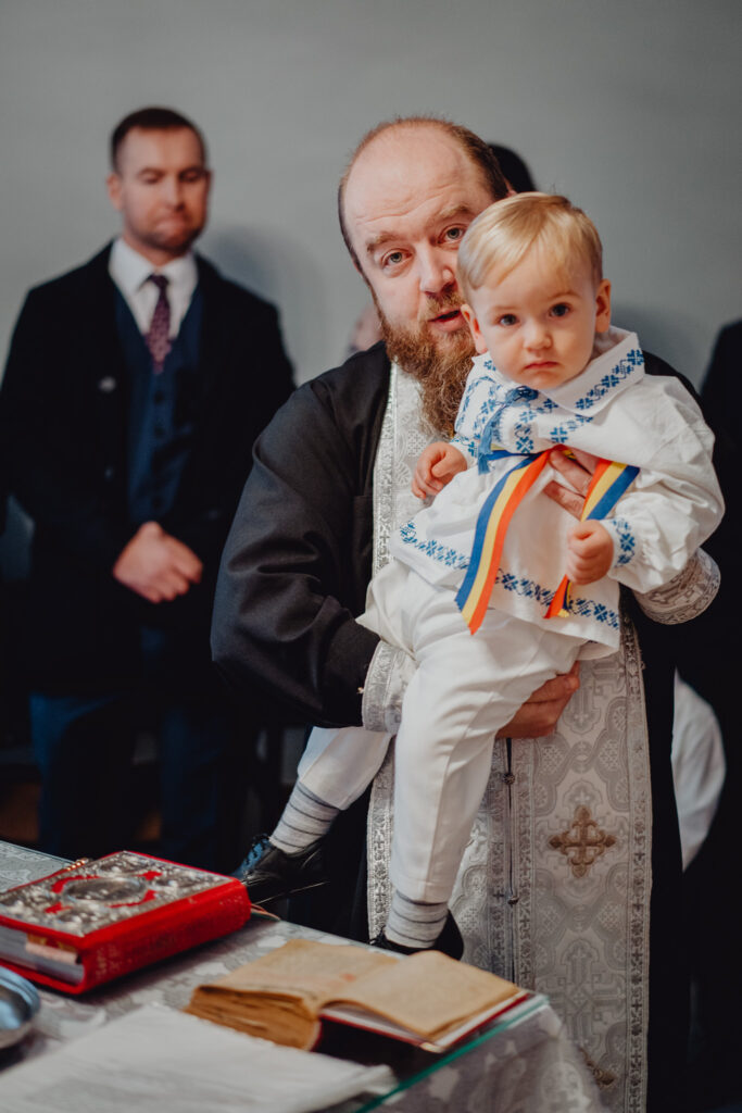 Prawosławny ksiądz trzyma na swych rękach chrzczone dziecko