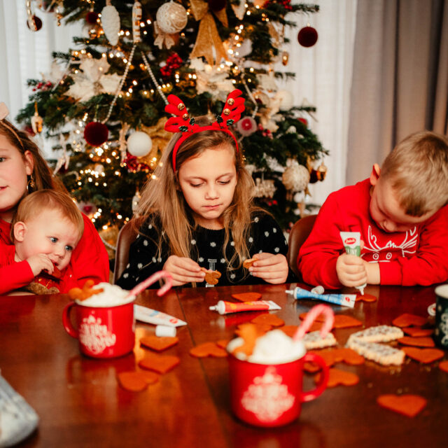 Wspólne pieczenie pierników przy stole podczas rodzinnej sesji świątecznej w domu.