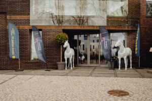 Wejście do Hotelu Traugutta. Widoczne są rozpoznawalne 2 białe konie po lewej i prawej stronie drzwi.