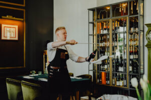 Kelner w Hotelu Traugutta otwiera szampana szablą.