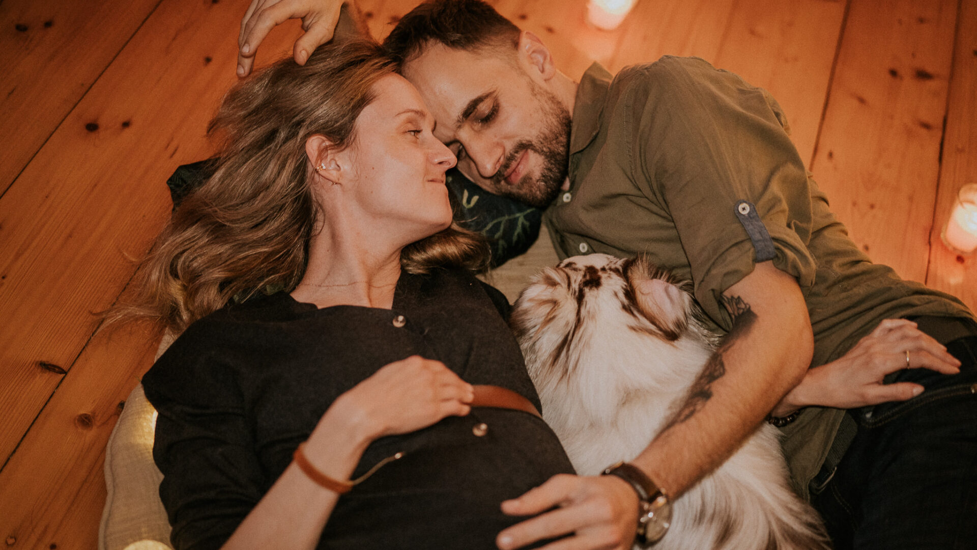 Pies wtulony pomiędzy swoich właścicieli podczas sesji ciążowej w domu